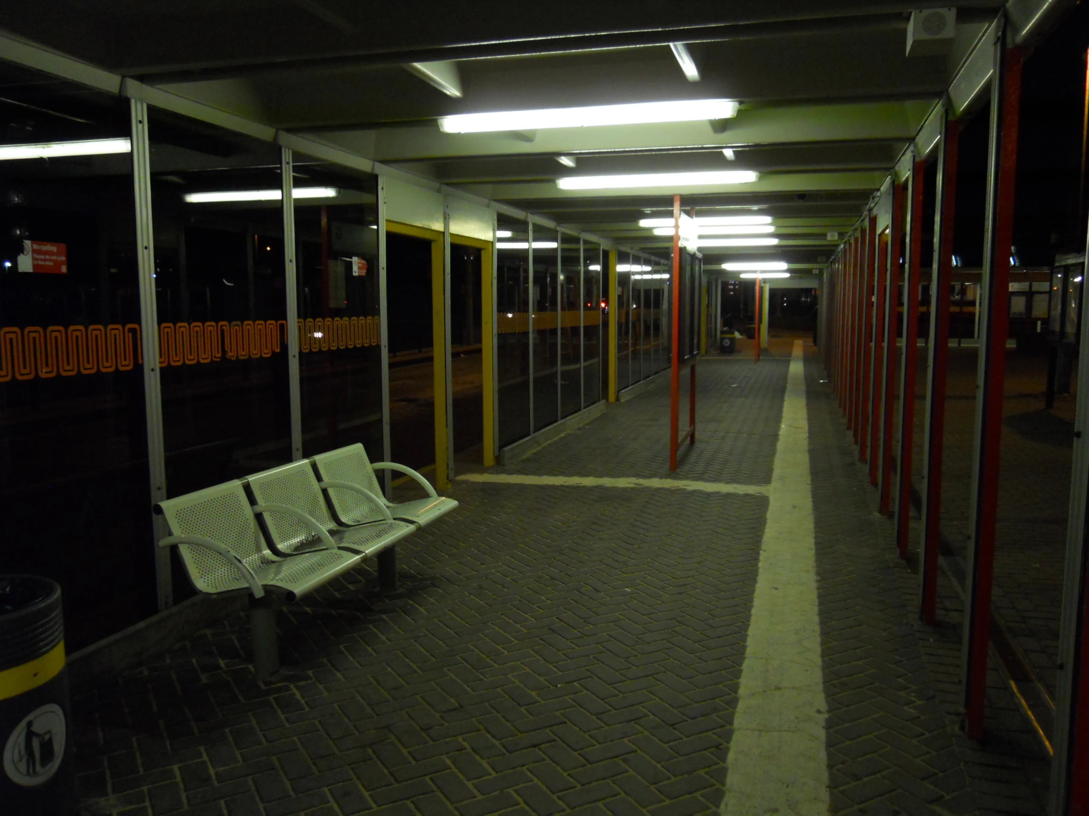 a empty public walkway at night, with a bench in between two buildings