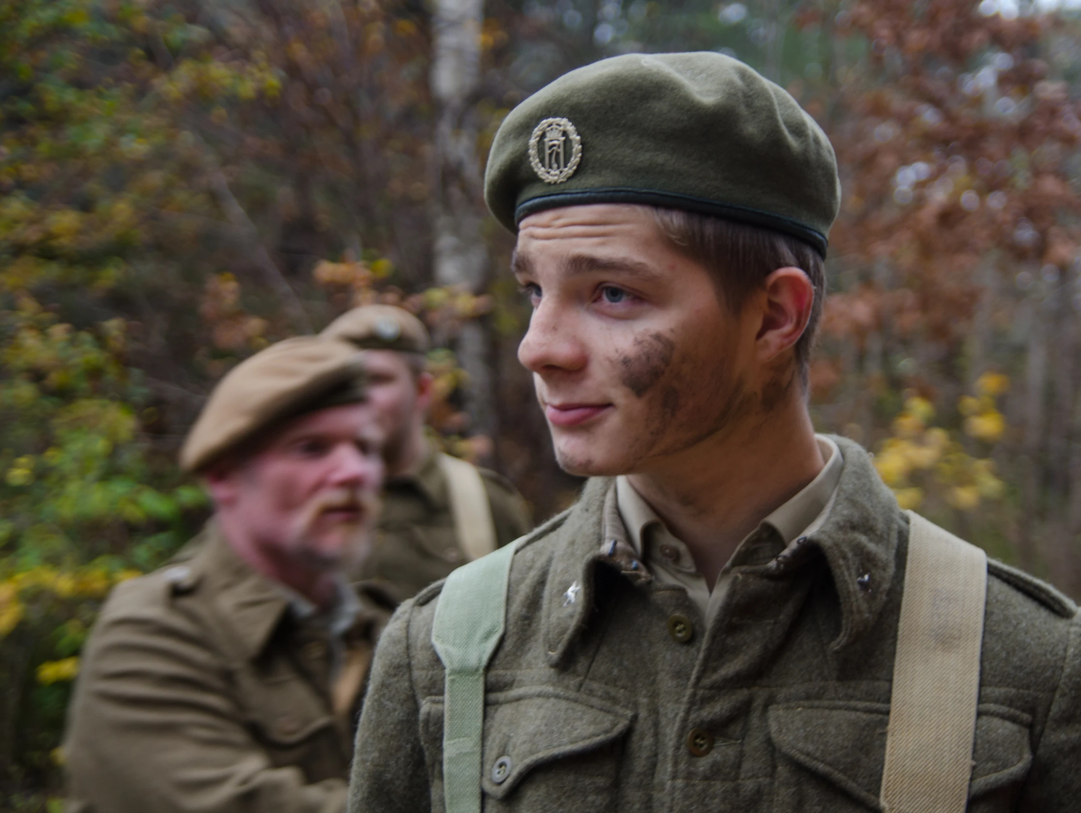 two men in uniforms walk through the woods