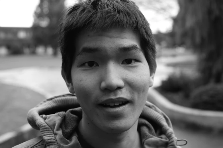 a young man smiling and standing outside by a street