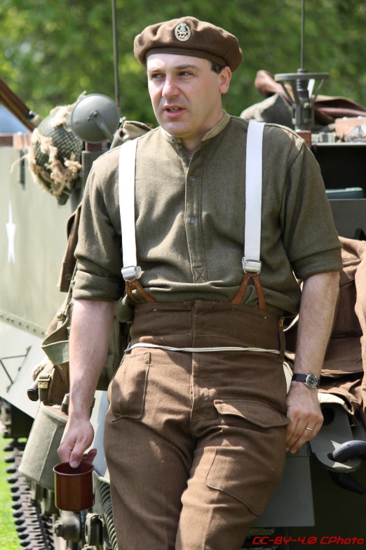 man in uniform posing near a row of military vehicles