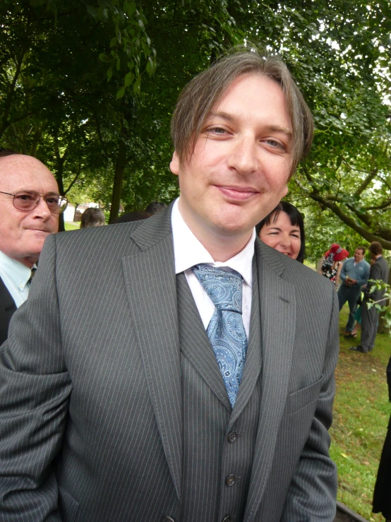 a man wearing a suit and tie smiling for a picture