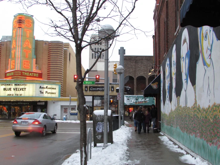 several people walk along the sidewalk on the side of the street