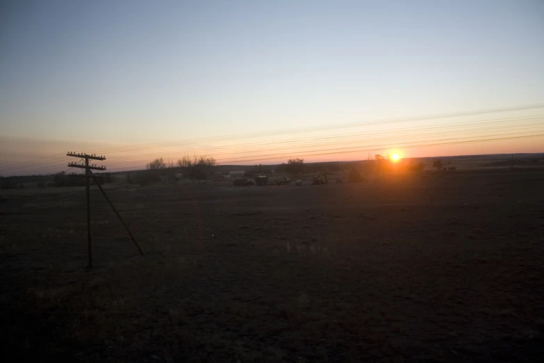 some cars sitting in a field near the sun setting