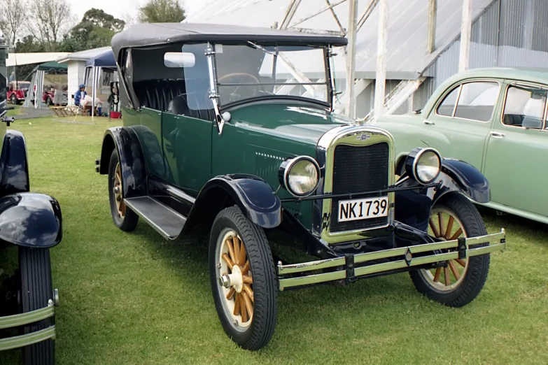 an antique car is parked on a grassy lot