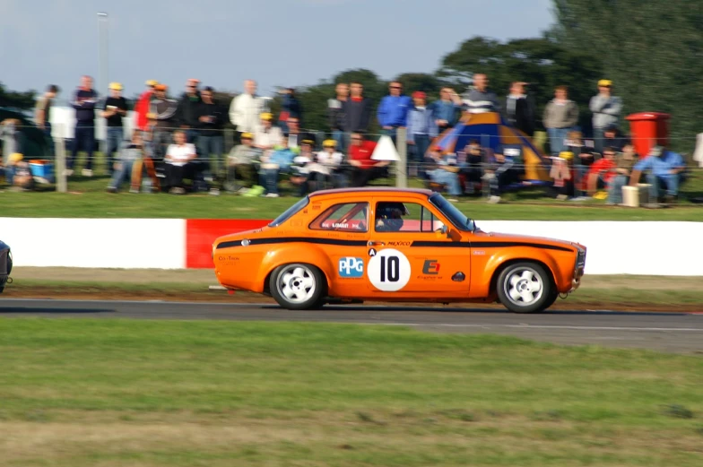 an orange car driving down the race track at a sporting event