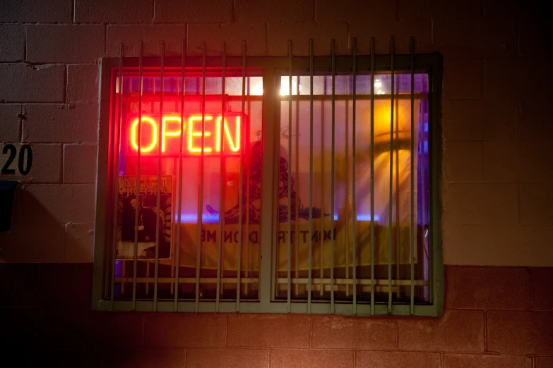 neon sign inside a metal barred window reading open