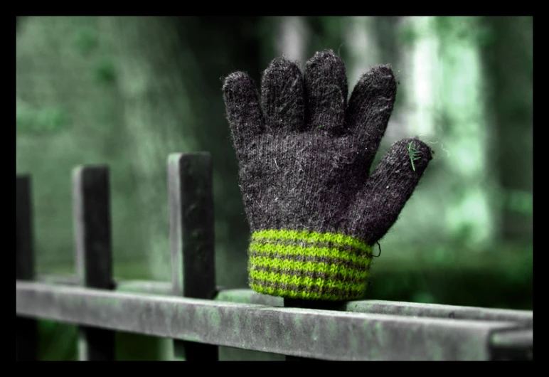 a pair of glove sitting on top of a metal fence