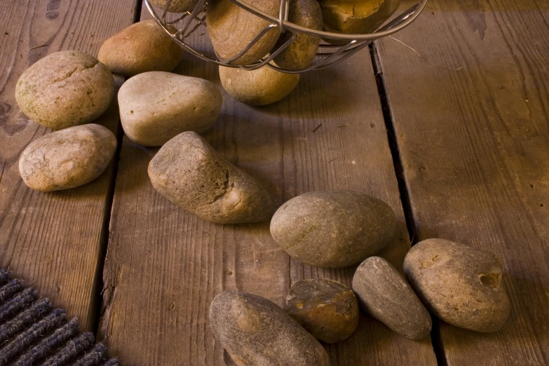 some potatoes are on a wooden table and there is one potato in the basket