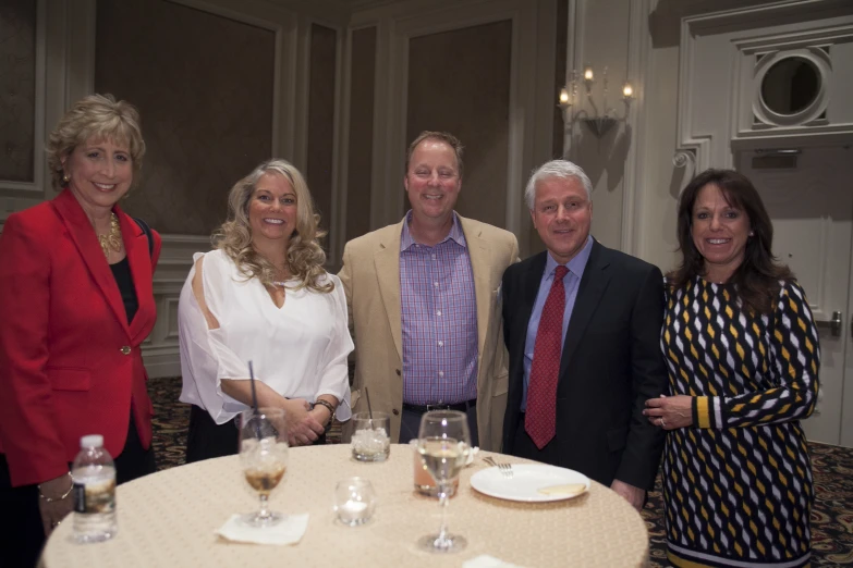 four people are smiling at the camera, two standing on a table