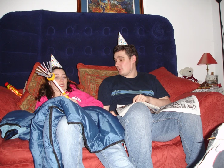 man and woman on the couch with cake hats on