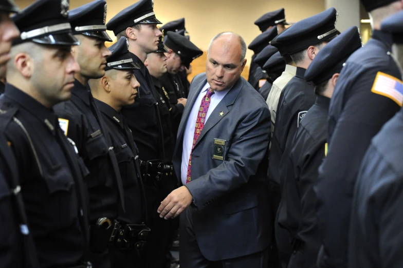 a man in a suit and tie surrounded by uniformed police