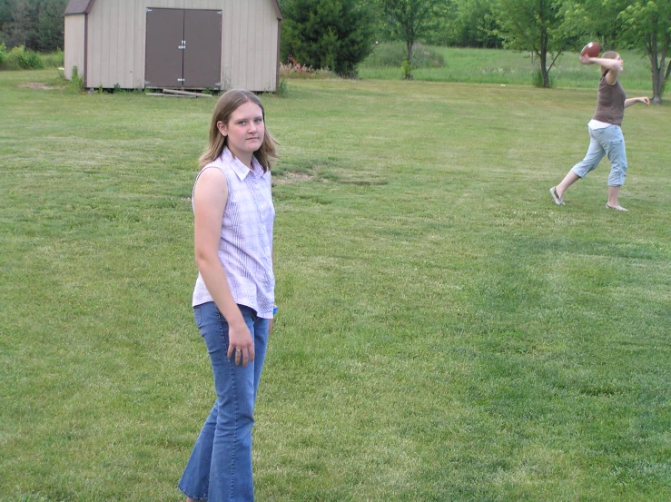 two girls in an open field throwing a frisbee