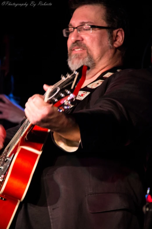 a man is playing an acoustic guitar while wearing a suit