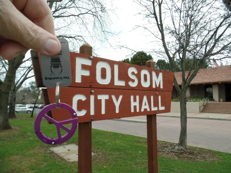 a hand holds up a piece of paper that reads, colloom city hall