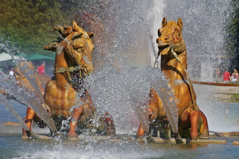 two horses are spraying water at the water fountain