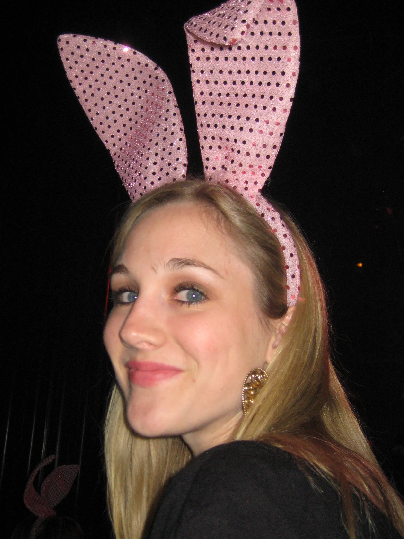 a girl with long blond hair wearing a pink polka dot bunny ears