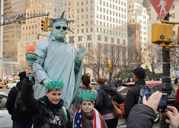 some children wearing hats around a statue of liberty
