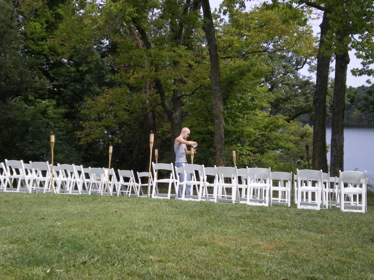 man standing on grass near rows of white chairs