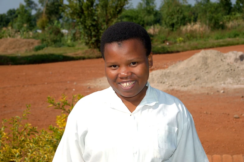 a young man smiling while standing in front of a field