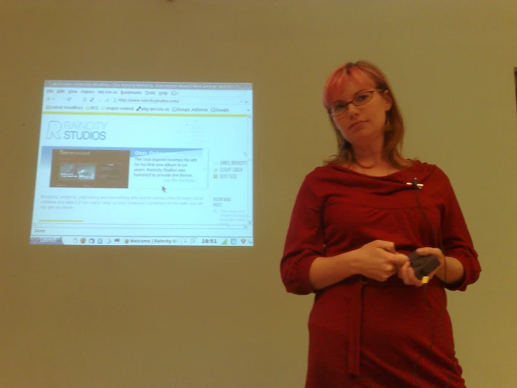 a woman in glasses standing in front of a projected screen