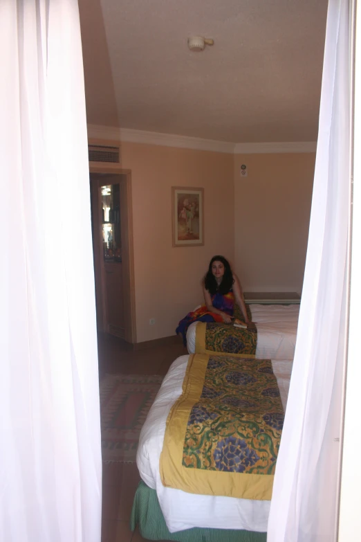 a woman is sitting on a bed looking out the window