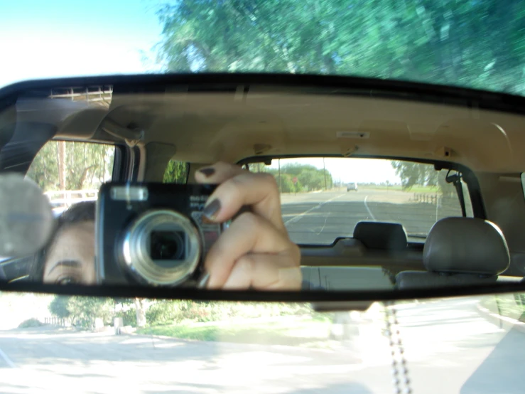 a woman's reflection is in the rear view mirror of a vehicle