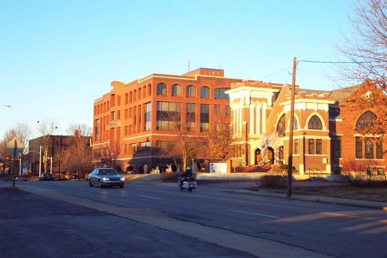 two vehicles are driving down a street in front of an old brick building