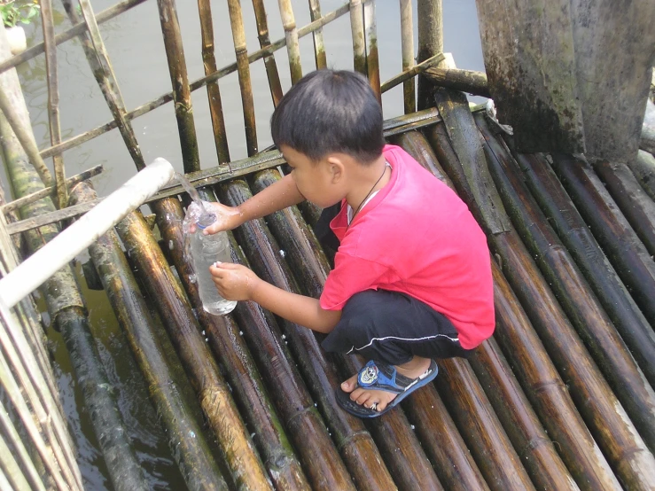 a small boy on a raft, kneeling down on the bamboo floor