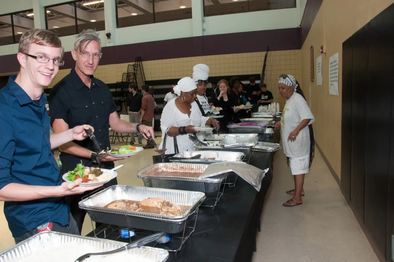 several people in a line getting food at a buffet