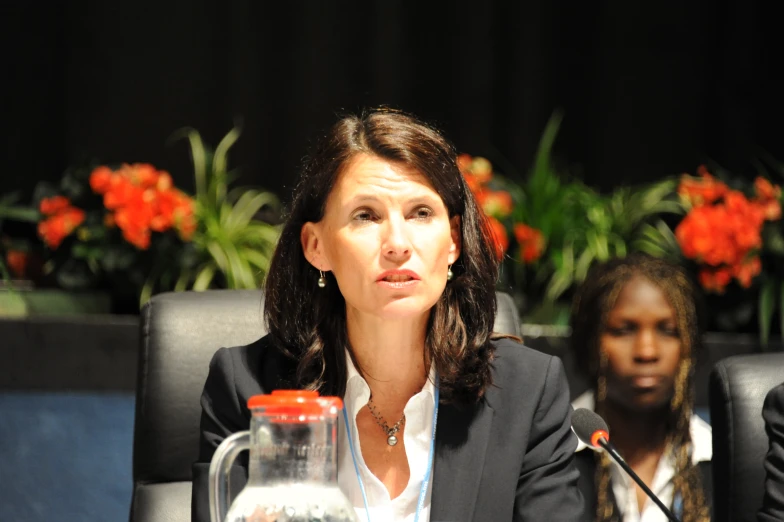 a woman sitting at a table in front of a jar of sand