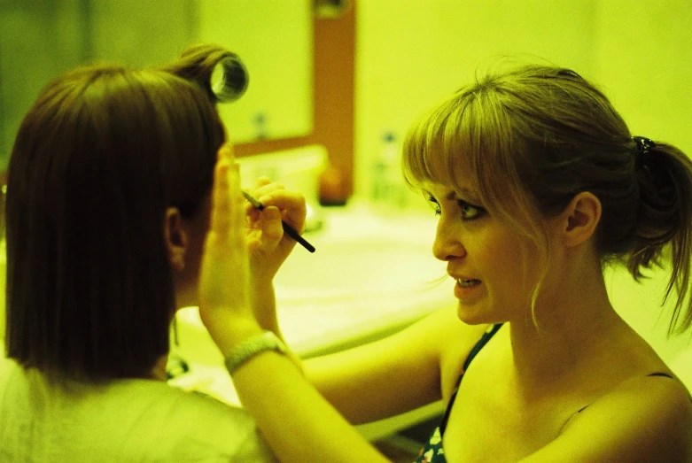 a woman is painting her hair in the mirror