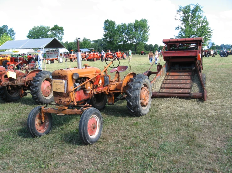 an orange tractor parked on top of a grass covered field