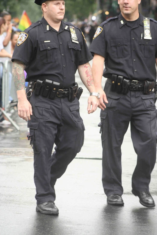 two police officers stand side by side while others watch