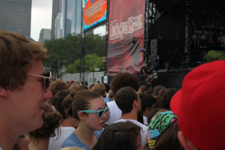 a crowd of people wearing sunglasses standing around and looking towards the stage