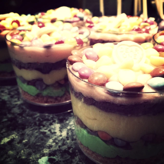 three desserts with candies, chocolate and marshmallows are in glass bowls