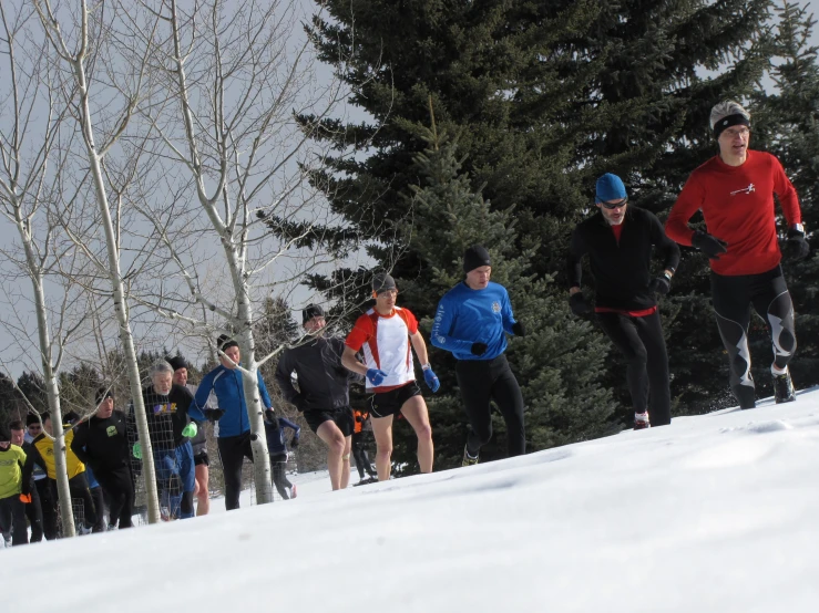 a group of people wearing sports gear run down the snow