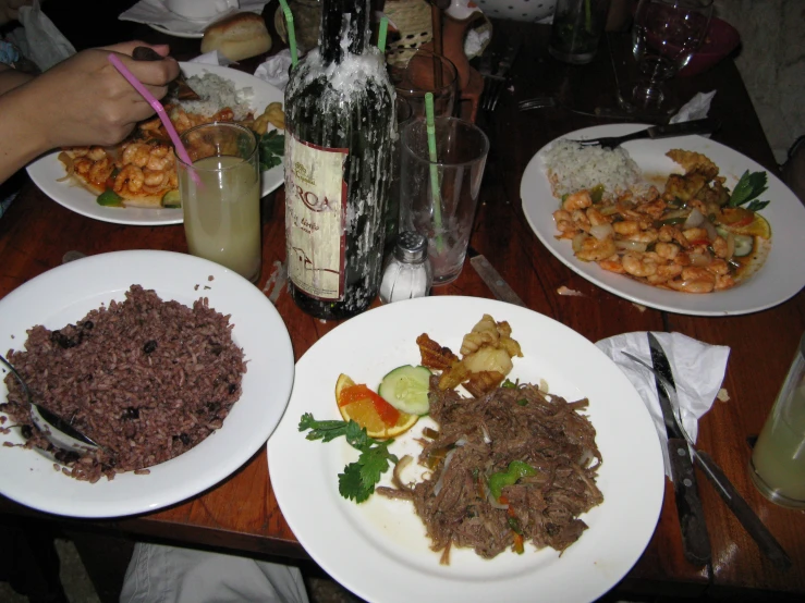 a wooden table filled with white plates full of food