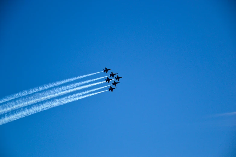 the four jets are flying close together, leaving vapor trails behind