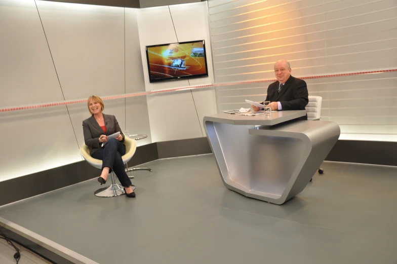 two people sitting down on the television set