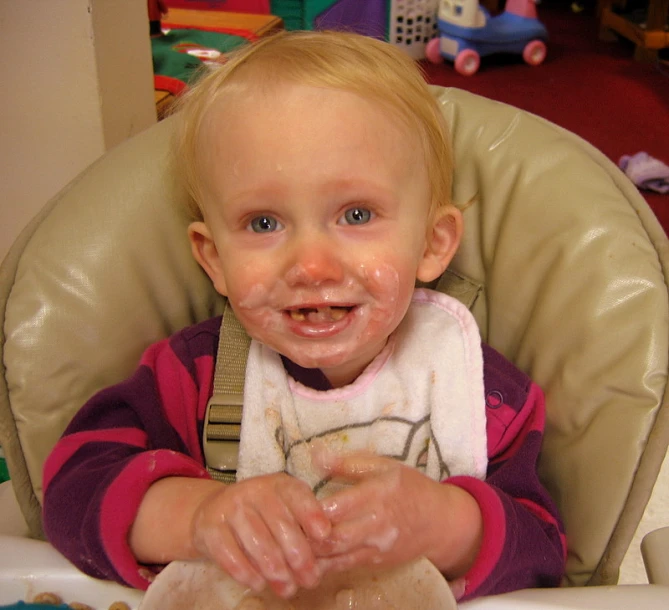 baby with dough all over his face sitting in a high chair