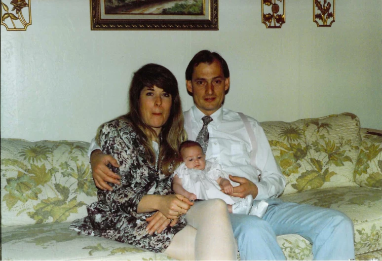 man and woman posing for po on couch with baby