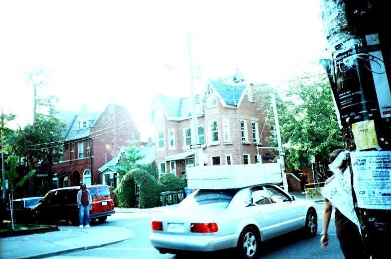 a white car driving down a street past buildings
