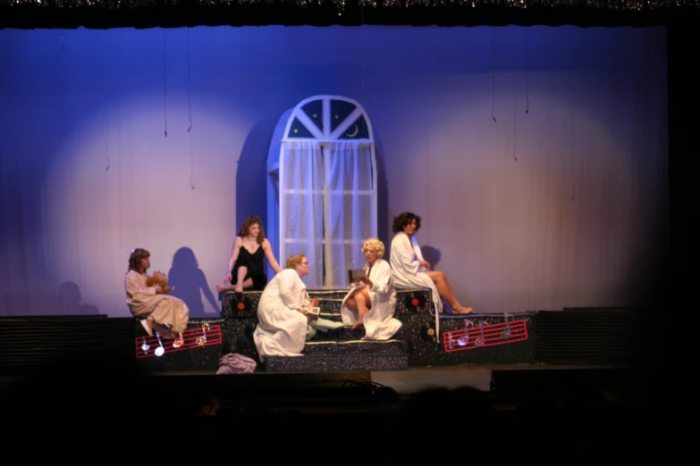 the women are sitting down on the stage