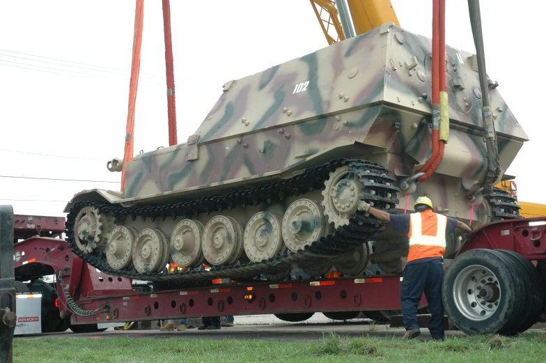 a man stands next to a large camouflage tank