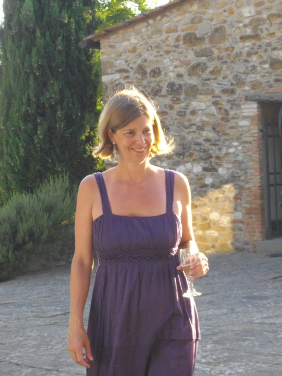 a woman holding a wine glass walking in front of a building