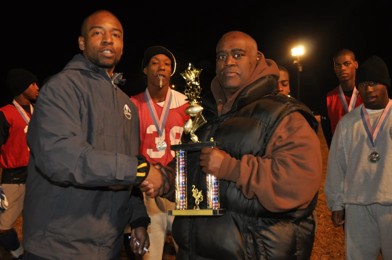 a group of men standing around each other holding a trophy