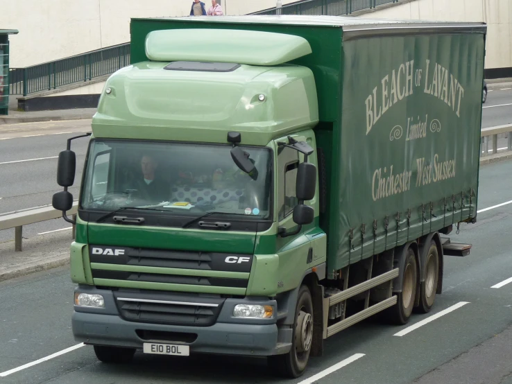 a semi - truck driving down a road by some buildings