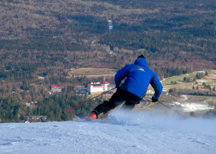 skier with blue jacket and red nose going down a slope