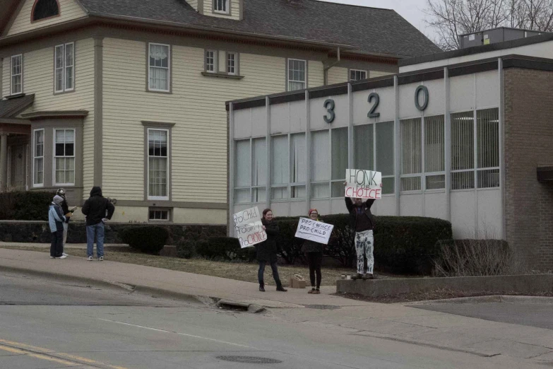 a group of protestors holding placards outside a building