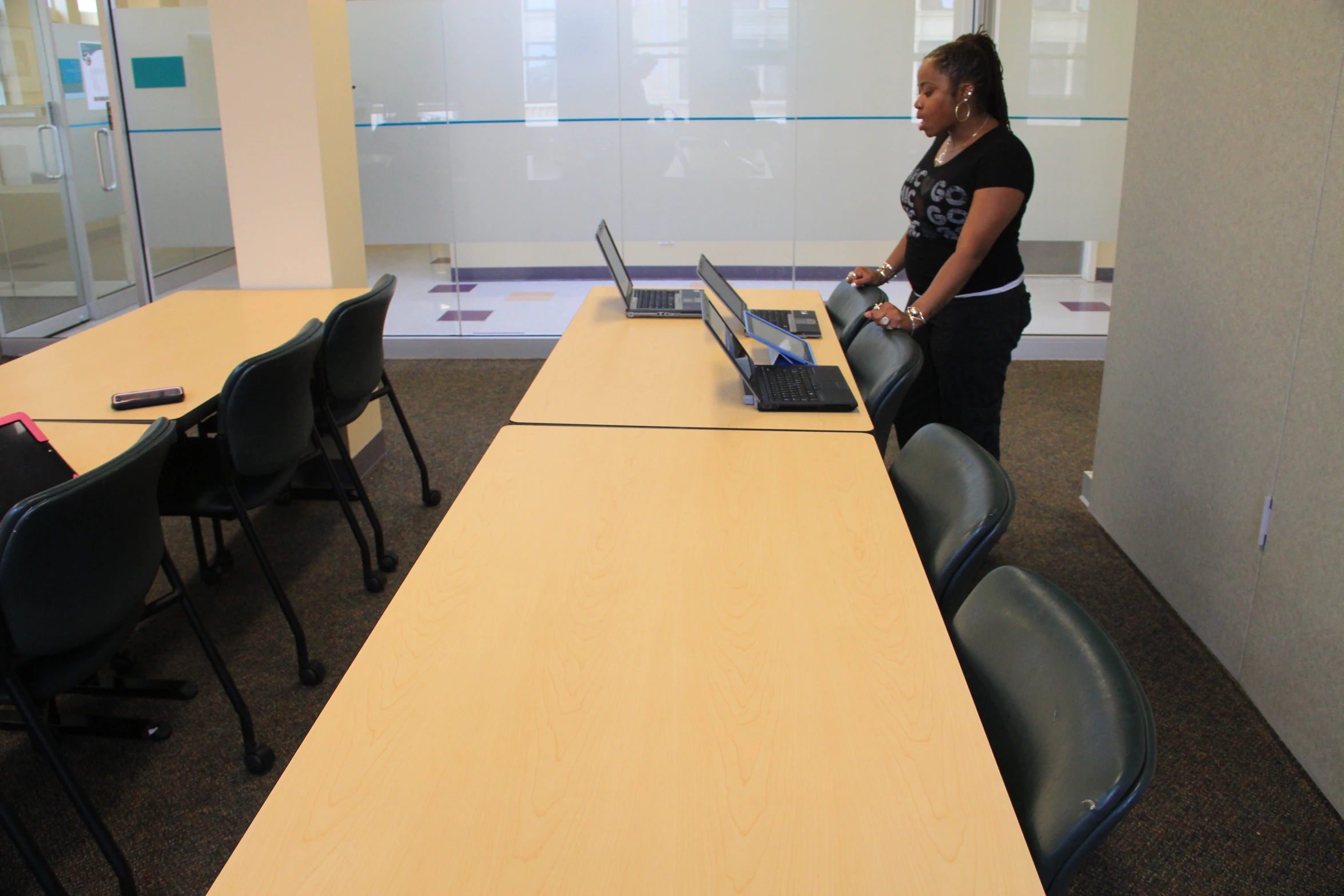 a woman stands at an open laptop computer in a modern office setting